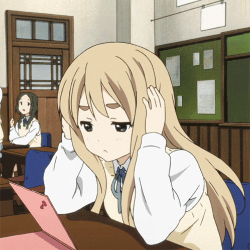 a girl with blonde hair is sitting at a desk looking at a pink laptop