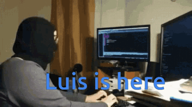 a man in a mask is typing on a keyboard with the words luis is here written in blue