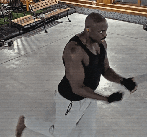 a man wearing a black tank top and white shorts is kneeling down