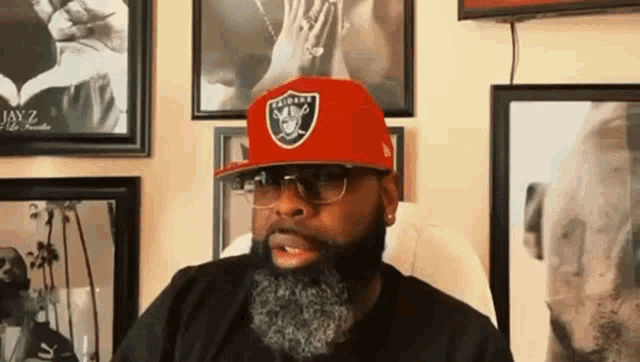 a man with a beard is wearing a raiders hat