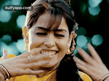 a close up of a woman covering her mouth with her hands while smiling .