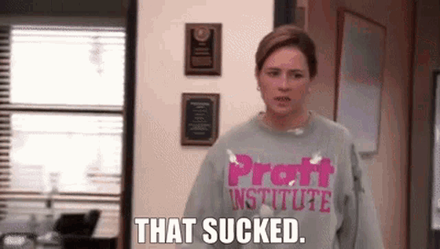 a woman wearing a sweatshirt that says that sucked is standing in a hallway .