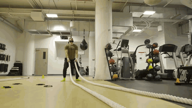 a man wearing a mask is holding a rope in a gym