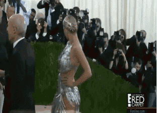 a woman in a silver dress is being photographed by a man in a suit with the words e red carpet below her