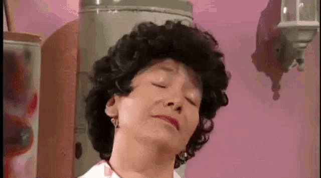 a woman with curly hair is making a funny face with her eyes closed .
