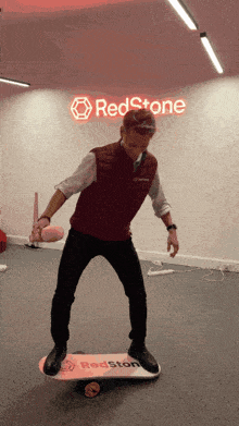 a man is balancing on a skateboard in front of a sign that says redstone