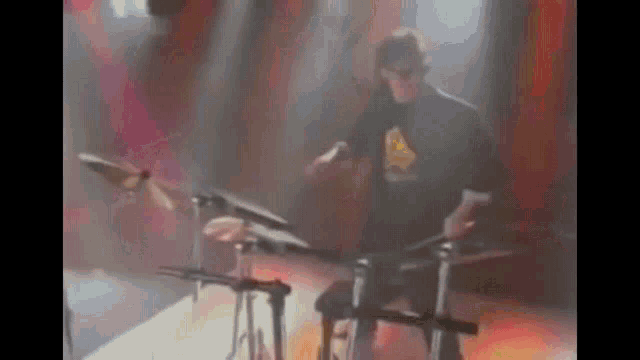 a man in a black shirt is playing drums