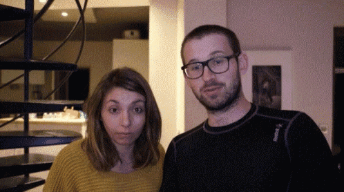 a man and a woman are posing for a picture with the man wearing glasses