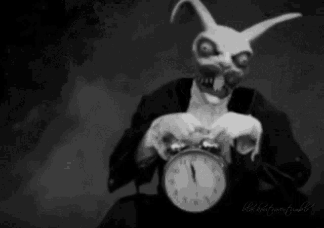 a man in a bunny mask is holding an alarm clock in his hands .