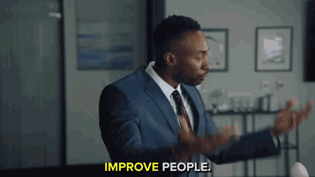 a man in a suit says improve people