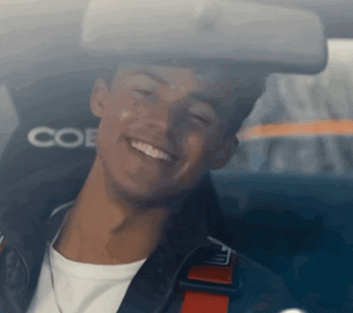a man is smiling in a car with the word coe on the seat
