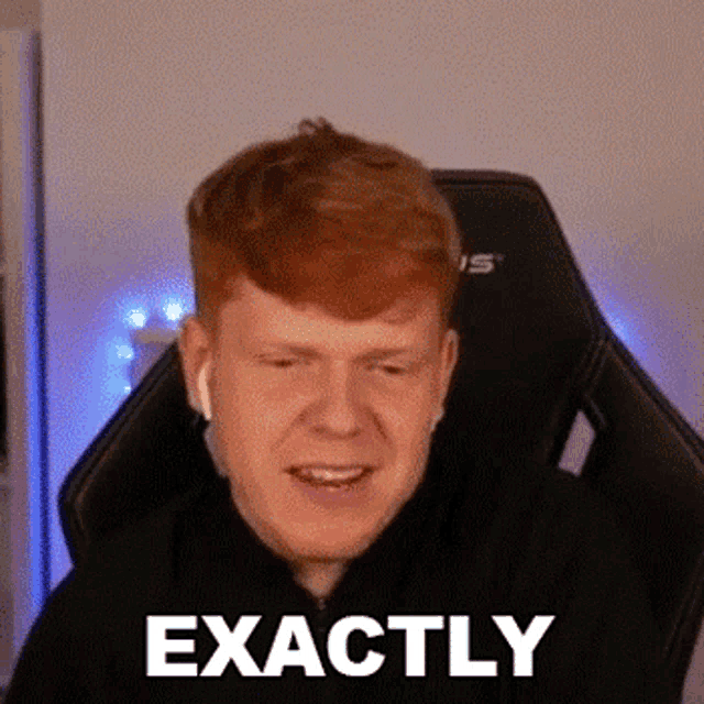a red haired man is sitting in a gaming chair and smiling .