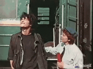 a man and a woman are standing next to each other in front of a green train .