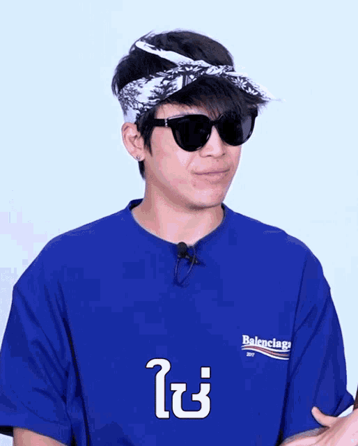 a man wearing sunglasses and a blue shirt that says balenciaga on it
