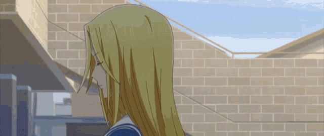 a girl with blonde hair is standing in front of a brick wall