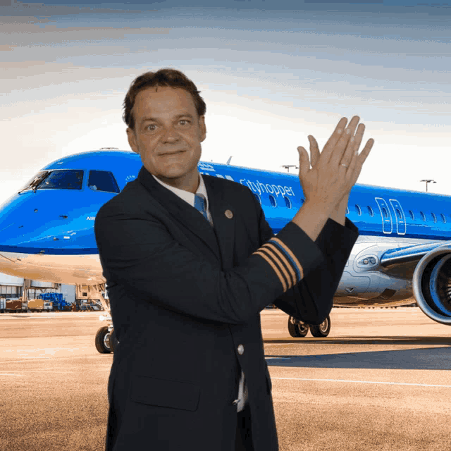 a pilot in front of a blue airplane that says cityhopper