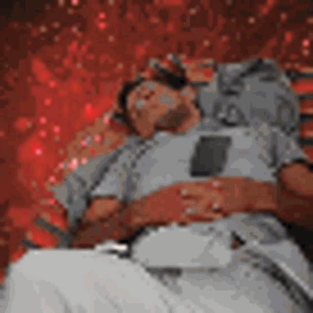 a man is laying on a bed looking at his phone .