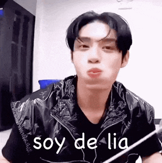 a young man wearing a black vest and a black shirt is making a funny face and saying `` soy de lia '' .