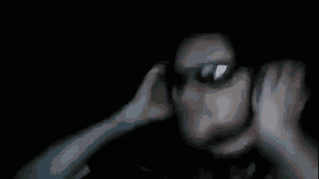 a blurry picture of a person covering their ears in the dark