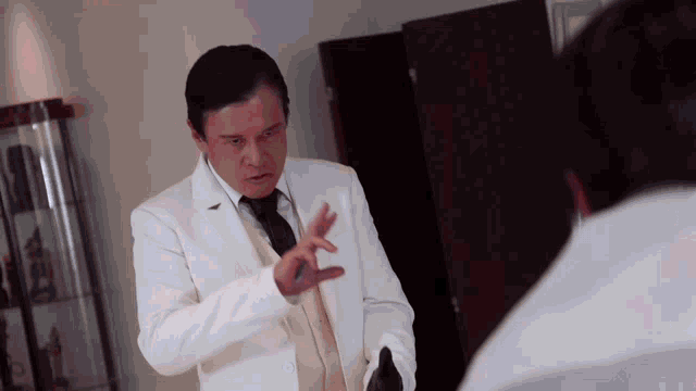 a man in a white coat and tie is talking to another person