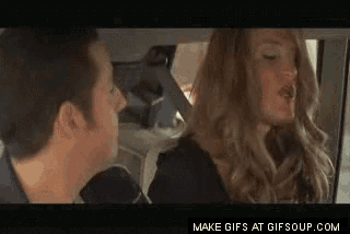 a man and a woman are sitting in a car and the woman is wearing a wig .