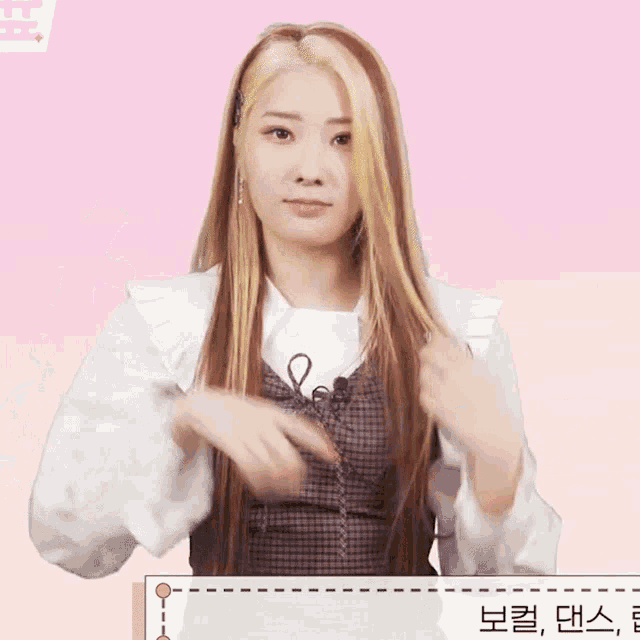 a woman with long blonde hair is standing in front of a pink background