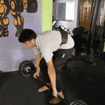 a man is lifting a barbell in a gym while wearing ear buds