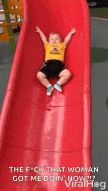 a little boy is laying on top of a red slide .