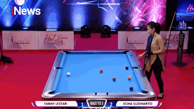a woman is playing pool in front of a news banner