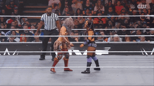 two women are wrestling in a ring with a referee and the words chicago on the screen