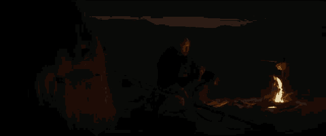 a man is standing next to a large statue of a monster in the dark .