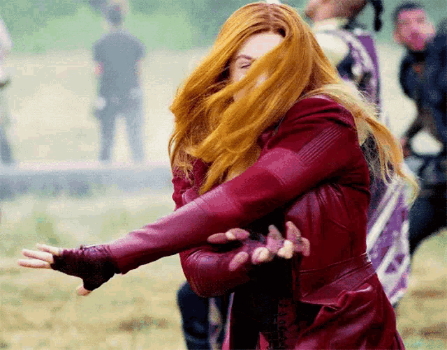 a woman with red hair is wearing a red jacket and gloves