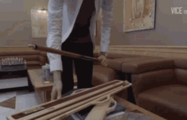 a man in a white shirt is holding a pool cue in a room