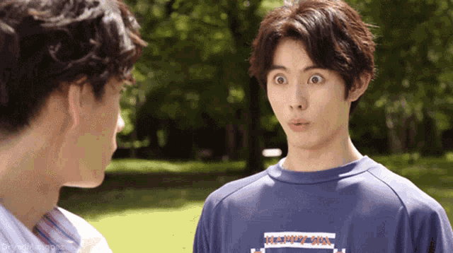 a man wearing a blue shirt that says kappa on it is talking to another man