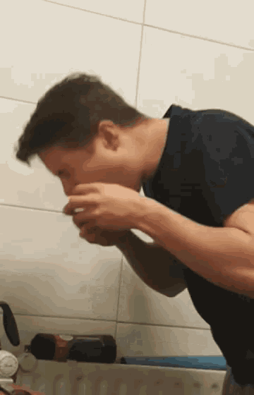 a man in a black shirt is drinking from a bottle of soda