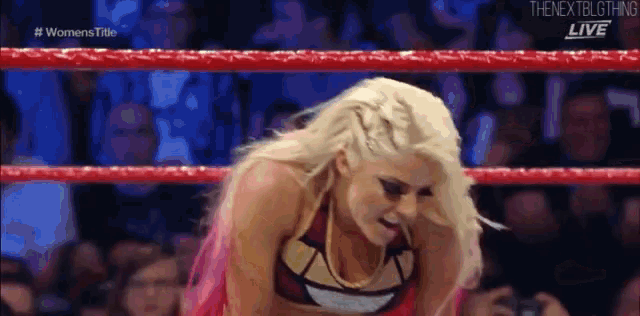 a woman is kneeling in a wrestling ring with her tongue out .