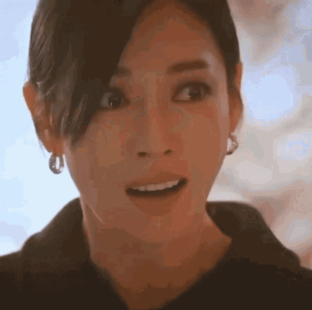a close up of a woman 's face with her mouth open and earrings .