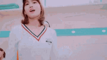 a woman wearing a baseball cap and a sweater is smiling and making a funny face .