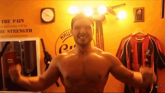 a shirtless man flexes his muscles in front of a sign that says the pain