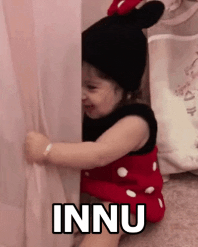 a little girl wearing a minnie mouse costume is peeking out from behind a curtain and says innu