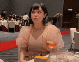 a woman in a pink dress is sitting at a table with a glass of wine
