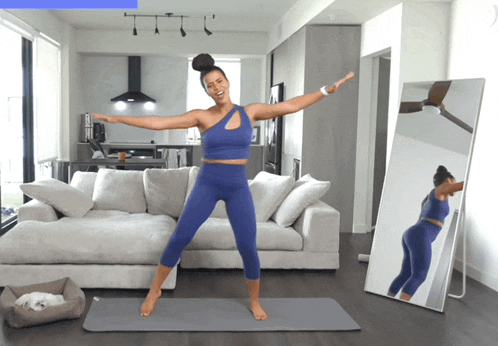 a woman stands on a yoga mat in front of a mirror