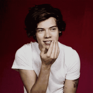 a young man with a tattoo on his arm is wearing a white shirt and covering his mouth with his hand
