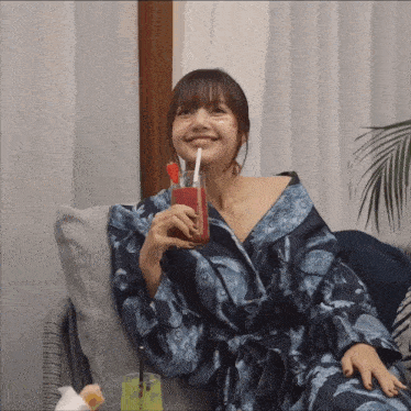 a woman in a robe is drinking a smoothie with strawberries