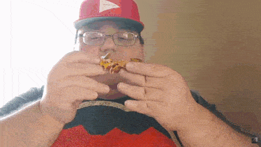 a man wearing a red hat and glasses is eating a piece of food