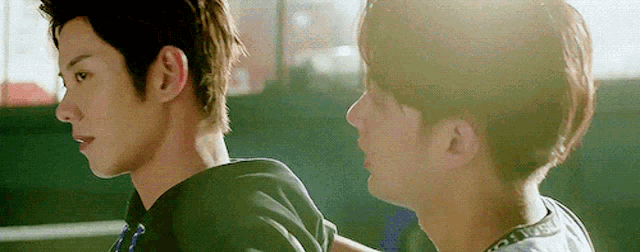 two young men are standing next to each other and looking at each other in a dark room .