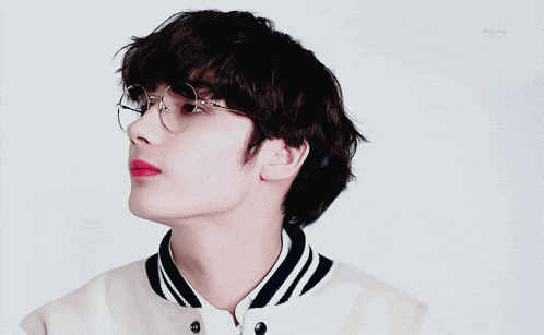 a young man wearing glasses and a white and black jacket