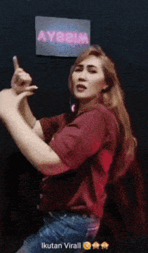 a woman giving a thumbs up in front of a sign that says ayasim