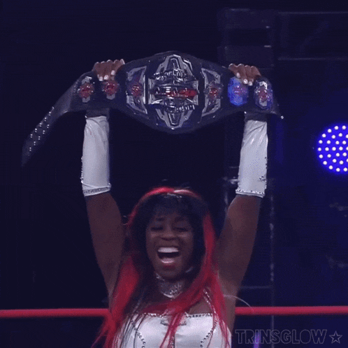 a woman with red hair is holding up a wrestling belt