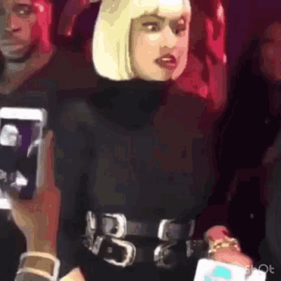 a woman with blonde hair is wearing a black turtleneck and a black belt